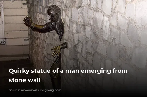 Quirky statue of a man emerging from a stone wall