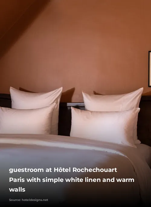 guestroom at Hôtel Rochechouart in Paris with simple white linen and warm brown walls