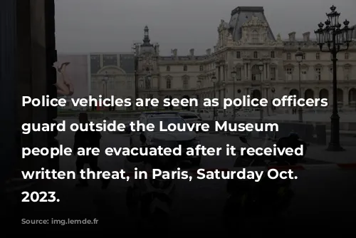 Police vehicles are seen as police officers stand guard outside the Louvre Museum as people are evacuated after it received a written threat, in Paris, Saturday Oct. 14, 2023. 