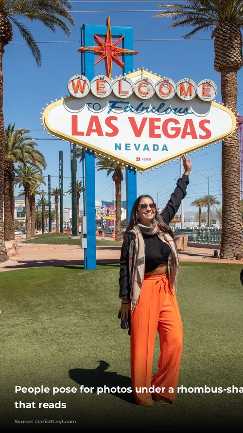 People pose for photos under a rhombus-shaped sign that reads 