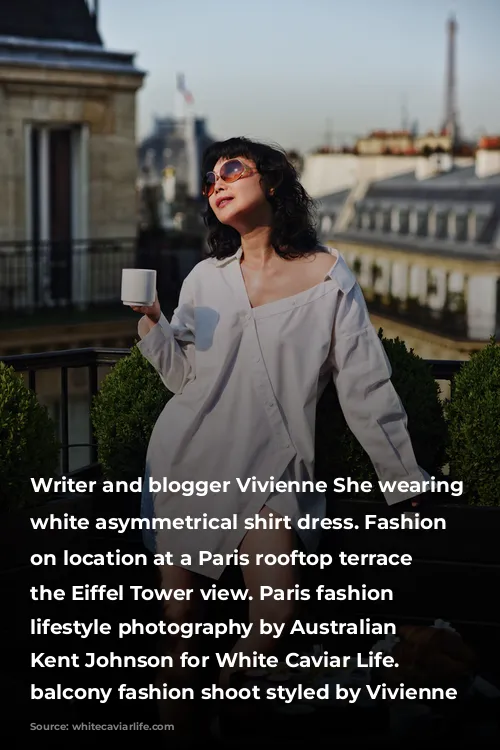 Writer and blogger Vivienne She wearing a white asymmetrical shirt dress. Fashion portraits on location at a Paris rooftop terrace with the Eiffel Tower view. Paris fashion and lifestyle photography by Australian photographer Kent Johnson for White Caviar Life. Paris balcony fashion shoot styled by Vivienne She.