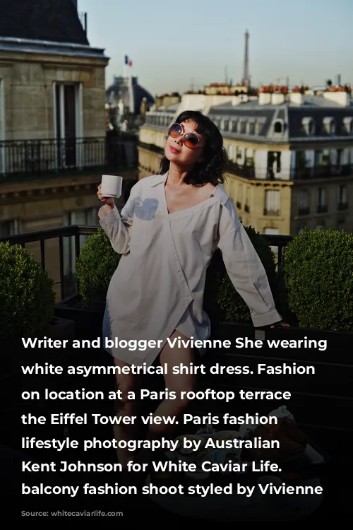 Writer and blogger Vivienne She wearing a white asymmetrical shirt dress. Fashion portraits on location at a Paris rooftop terrace with the Eiffel Tower view. Paris fashion and lifestyle photography by Australian photographer Kent Johnson for White Caviar Life. Paris balcony fashion shoot styled by Vivienne She.