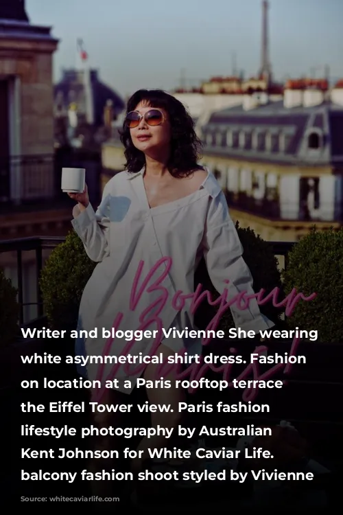 Writer and blogger Vivienne She wearing a white asymmetrical shirt dress. Fashion portraits on location at a Paris rooftop terrace with the Eiffel Tower view. Paris fashion and lifestyle photography by Australian photographer Kent Johnson for White Caviar Life. Paris balcony fashion shoot styled by Vivienne She.