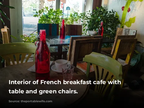 Interior of French breakfast cafe with wooden table and green chairs.