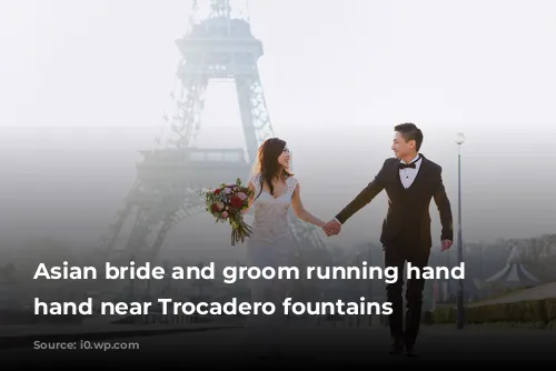 Asian bride and groom running hand in hand near Trocadero fountains