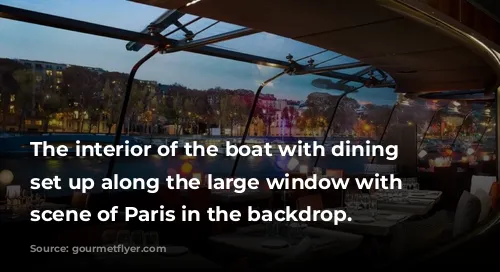 The interior of the boat with dining tables set up along the large window with night scene of Paris in the backdrop.