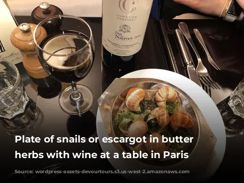 Plate of snails or escargot in butter and herbs with wine at a table in Paris