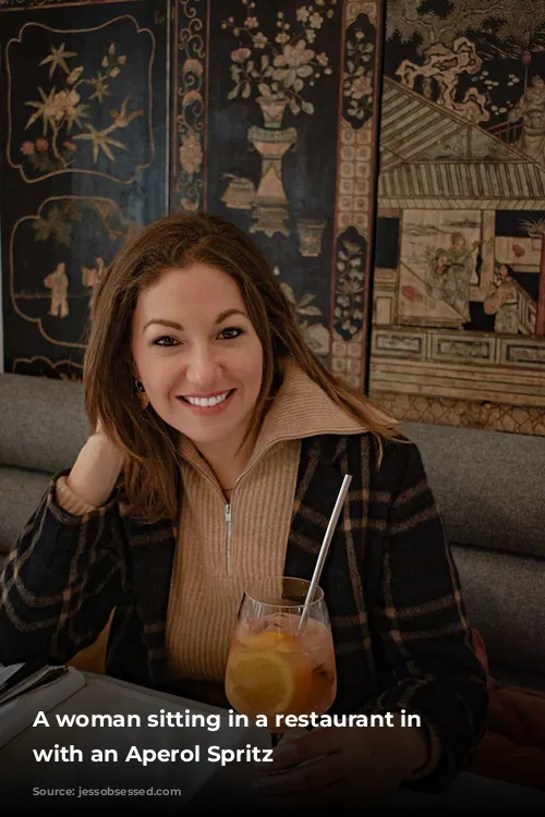 A woman sitting in a restaurant in Paris with an Aperol Spritz