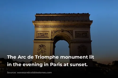 The Arc de Triomphe monument lit up in the evening in Paris at sunset.