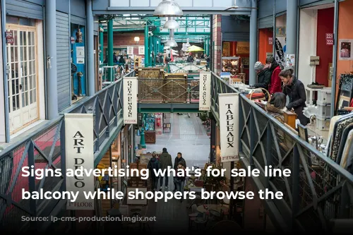 Signs advertising what's for sale line the balcony while shoppers browse the stores