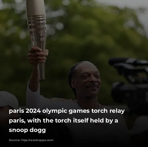 paris 2024 olympic games torch relay in paris, with the torch itself held by a smiling snoop dogg