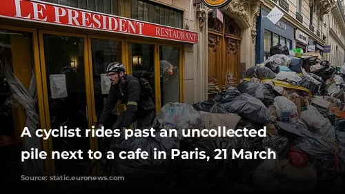 A cyclist rides past an uncollected rubbish pile next to a cafe in Paris, 21 March 2023.