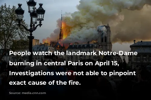 People watch the landmark Notre-Dame Cathedral burning in central Paris on April 15, 2019- Investigations were not able to pinpoint the exact cause of the fire. 