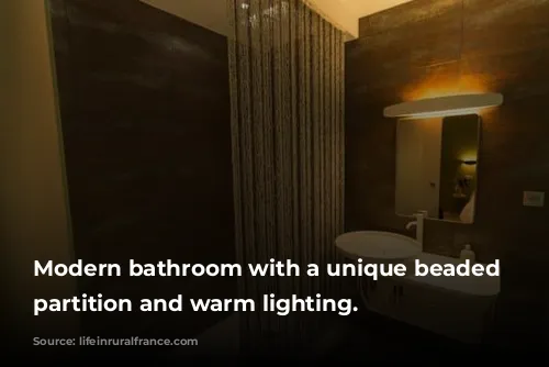 Modern bathroom with a unique beaded shower partition and warm lighting.