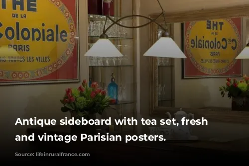 Antique sideboard with tea set, fresh flowers, and vintage Parisian posters.