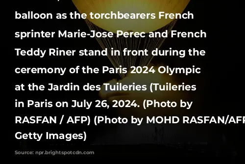 TOPSHOT - The cauldron, with the Olympic flame lit, lifts off while attached to a balloon as the torchbearers French former sprinter Marie-Jose Perec and French judoka Teddy Riner stand in front during the opening ceremony of the Paris 2024 Olympic Games at the Jardin des Tuileries (Tuileries Garden) in Paris on July 26, 2024. (Photo by MOHD RASFAN / AFP) (Photo by MOHD RASFAN/AFP via Getty Images)