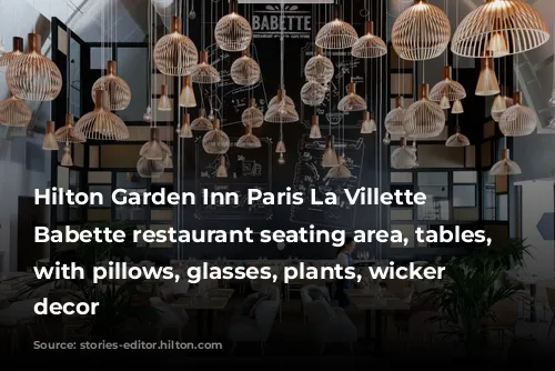 Hilton Garden Inn Paris La Villette - Babette restaurant seating area, tables, chairs with pillows, glasses, plants, wicker basket decor