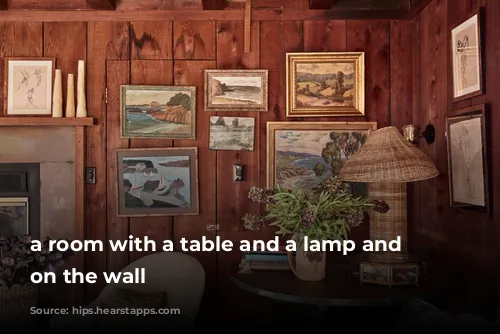 a room with a table and a lamp and pictures on the wall